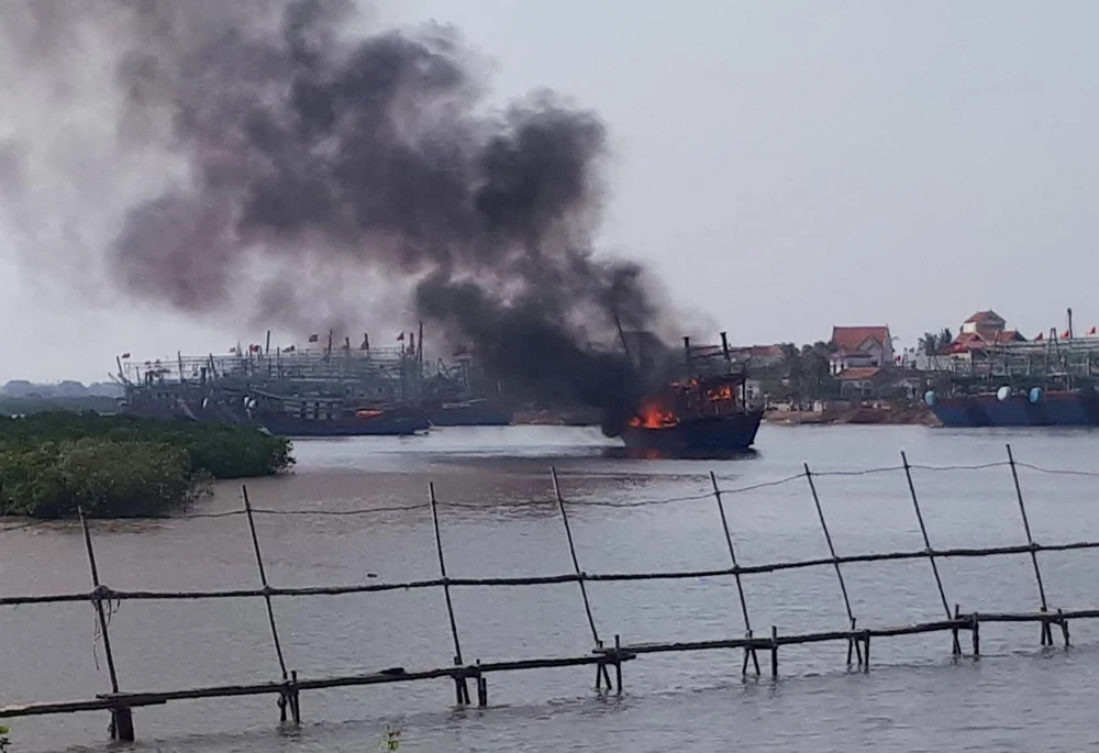 Tàu cá cháy ngùn ngụt tại khu vực cảng Lạch Quèn. (Ảnh: TTXVN phát)