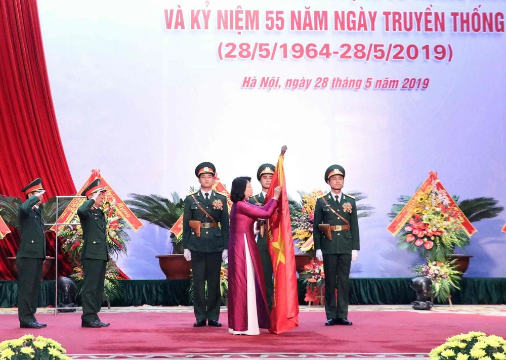 Phó Chủ tịch nước Đặng Thị Ngọc Thịnh gắn Danh hiệu Anh hùng Lực lượng Vũ trang Nhân dân lên lá cờ truyền thống của Cục Đối ngoại. (Ảnh: Văn Điệp/TTXVN)