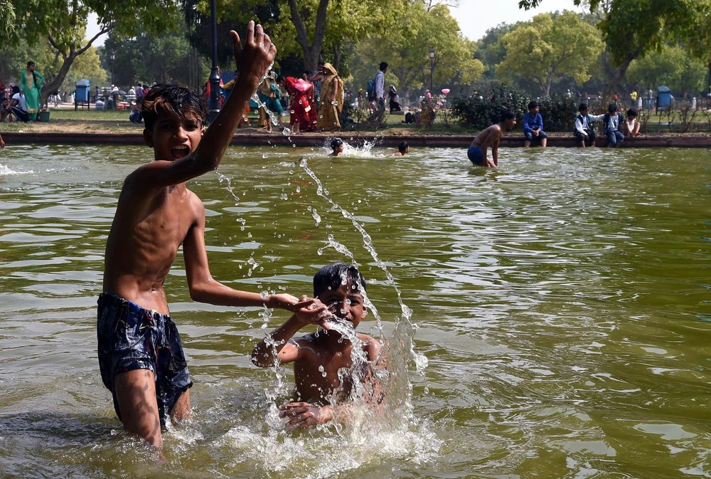 Trẻ em giải nhiệt tránh nóng tại một ao nước ở New Delhi của Ấn Độ ngày 7/6. (Ảnh: THX/TTXVN)