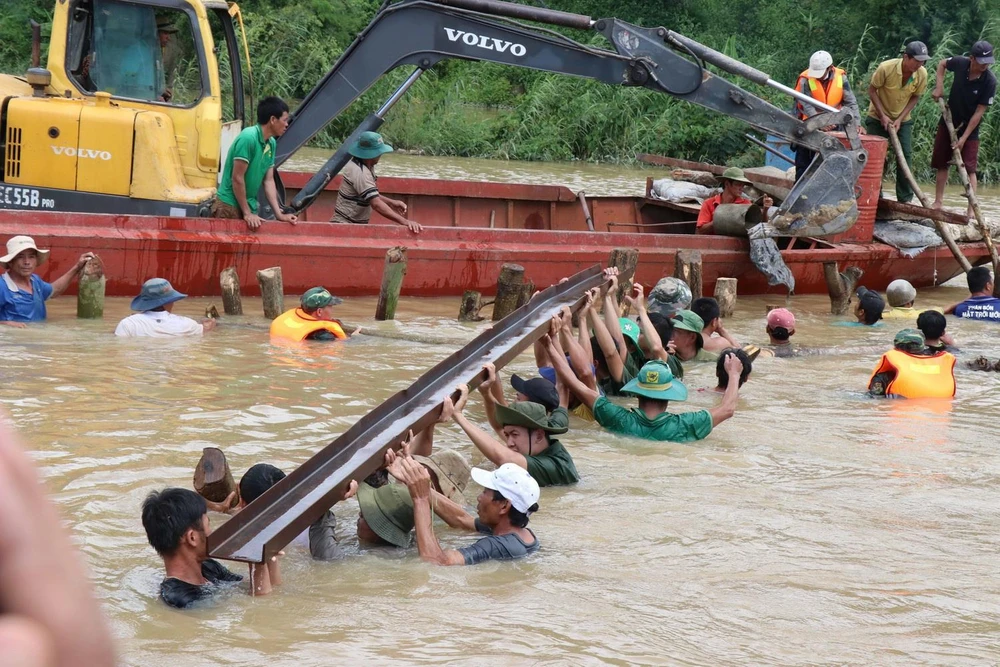 Các lực lượng chức năng cùng người dân dùng cọc và lưới sắt để làm kè đoạn đê bị vỡ. (Ảnh: Tuấn Anh/TTXVN)