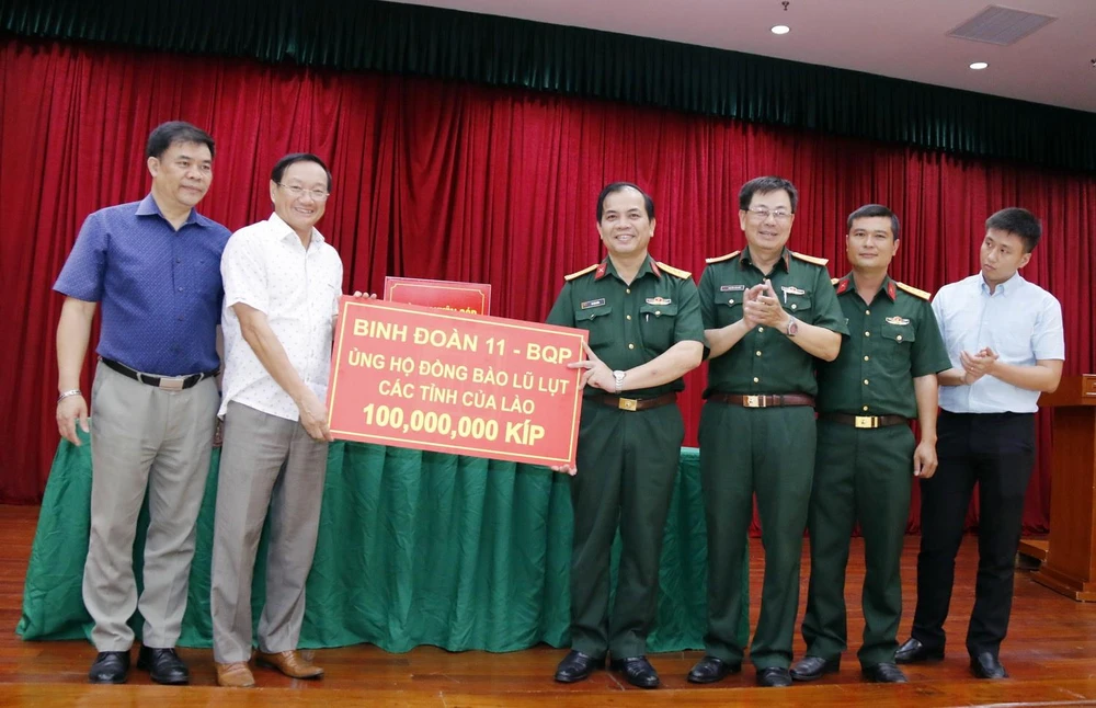 Đại diện Binh đoàn 11 thuộc Bộ Quốc phòng Việt Nam, trao số tiền ủng hộ 100 triệu kíp (hơn 11.000 USD). (Ảnh: Phạm Kiên/TTXVN)