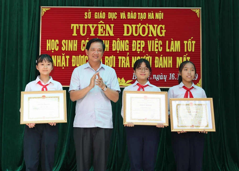 Phó Giám đốc Sở Giáo dục và Đào tạo Hà Nội Phạm Xuân Tiến trao Giấy khen của Giám đốc Sở cho 3 học sinh. (Ảnh: Thanh Tùng/TTXVN)