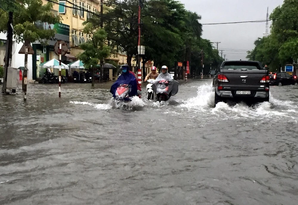 Nhiều tuyến đường thành phố Vinh bị ngập khiến các phương tiện tham gia giao thông gặp nhiều khó khăn. (Ảnh: Tá Chuyên/TTXVN)