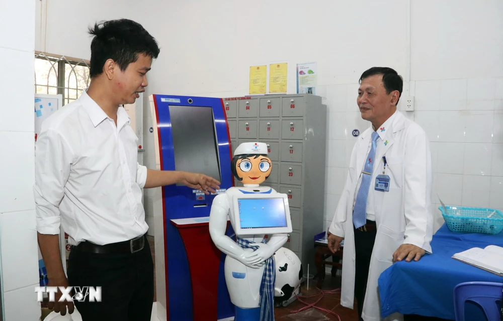 Kỹ sư Võ Hồng Quân, phụ trách Trung tâm Công nghệ thông tin, Bệnh viện Quân dân y miền Đông (trái) giới thiệu robot thông minh Cô Tấm hỗ trợ người bệnh. (Ảnh: Xuân Khu/TTXVN)