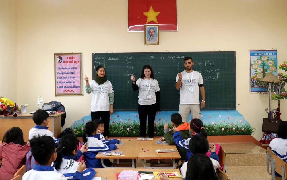 Các tình nguyện viên hướng dẫn các em học sinh trường Tiểu học và THCS Lê Văn Tám (thị trấn Sa Pa) học văn hóa bằng tiếng Anh. (Ảnh: Quốc Khánh/TTXVN)