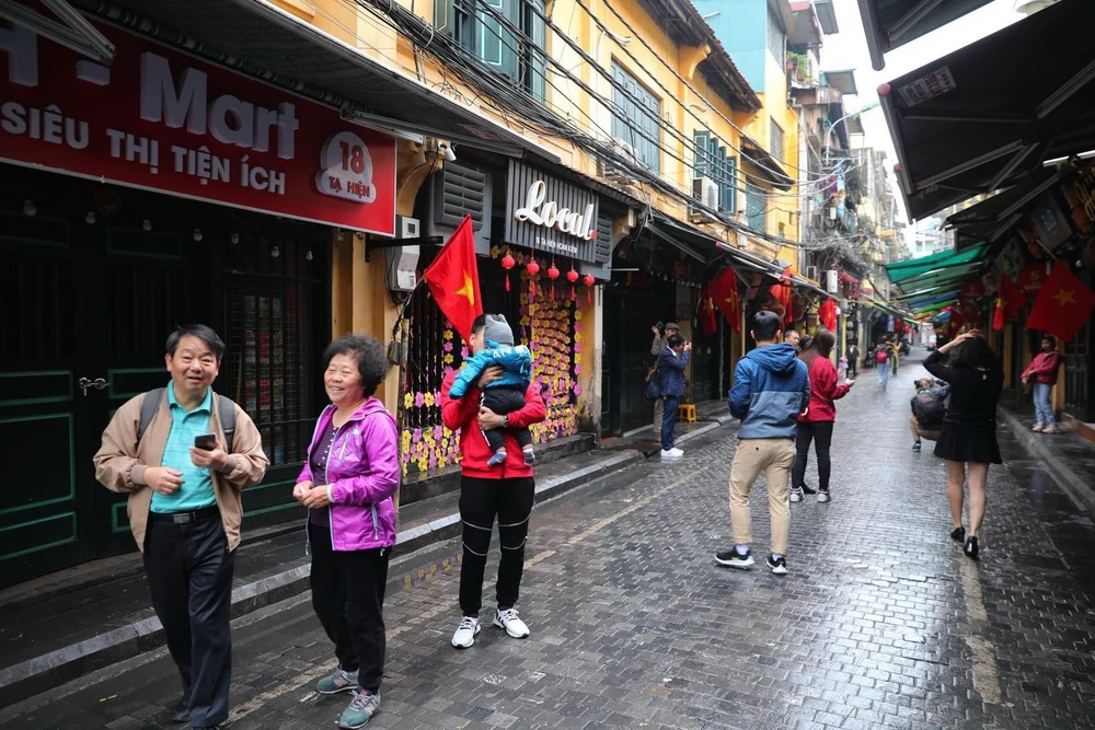 Khách du lịch quốc tế trải nghiệm không khí sáng mùng 1 Tết tại phố Tạ Hiện. (Ảnh: Thành Đạt/TTXVN)