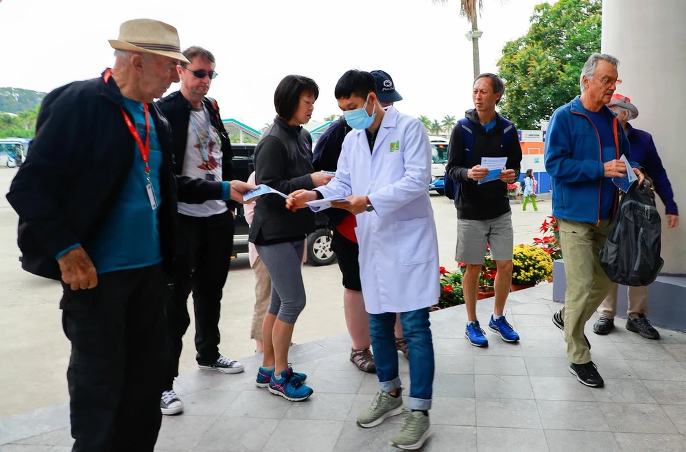  Cán bộ nhân viên Trung tâm Kiểm soát bệnh tật phát tờ rơi truyền thông về nCov cho khách du lịch đến thăm quan vịnh Hạ Long tại bến tầu du lịch Tuần Châu-Hạ Long. (Ảnh: TTXVN phát) 