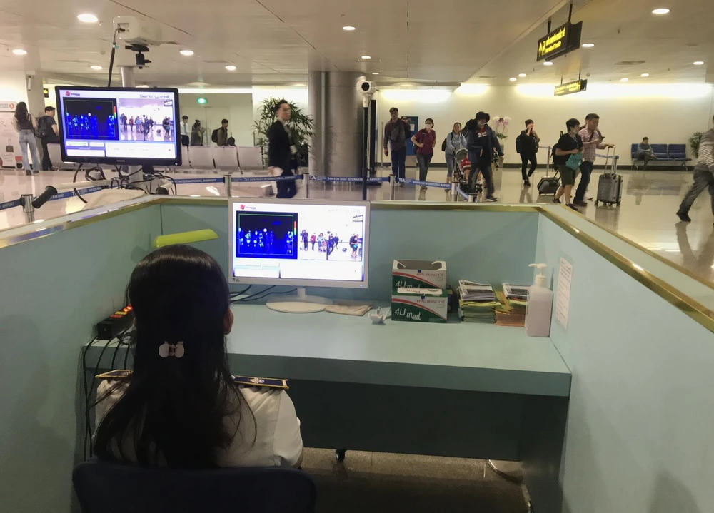 Nhân viên sân bay kiểm tra màn hình hiển thị máy quét thân nhiệt đối với hành khách quốc tế đến Việt Nam. (Ảnh: Đinh Hằng/TTXVN)
