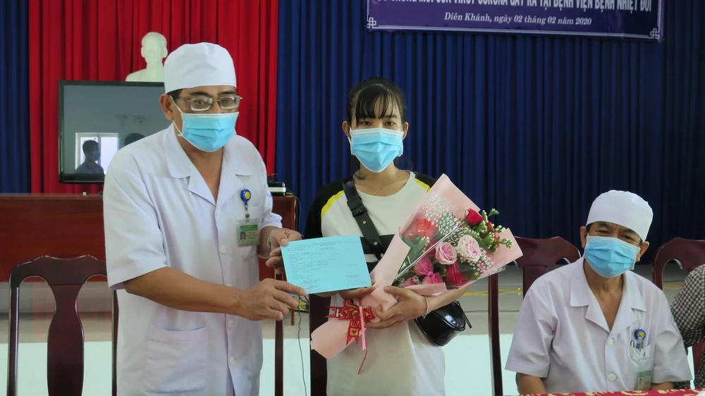 Phó Giám đốc Bệnh viện Bệnh Nhiệt đới Khánh Hòa Nguyễn Vũ Quốc Bình tặng hoa và trao giấy xuất viện cho bệnh nhân Lê Thị Thu H. (Ảnh: Phan Sáu/TTXVN)