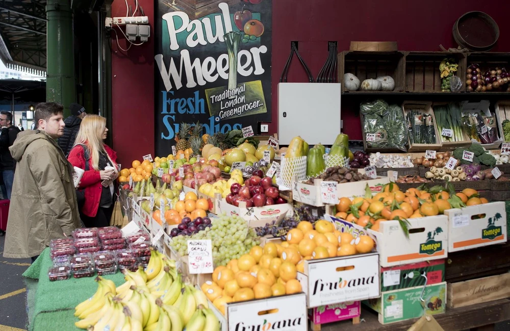 Khách hàng chọn mua hoa quả và rau tại một chợ ở London, Anh. (Ảnh: AFP/TTXVN)