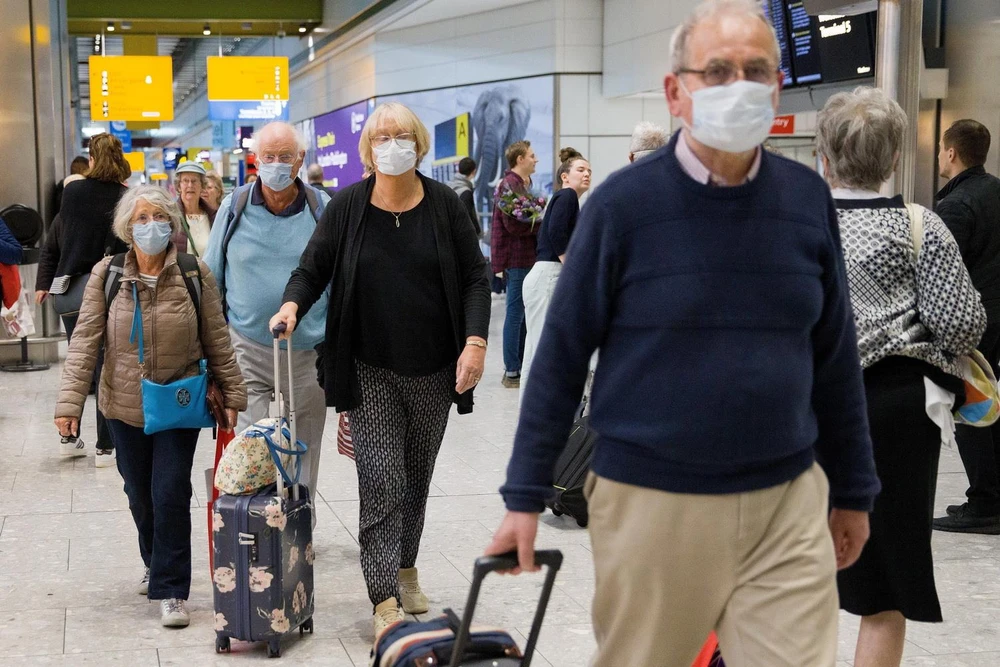 Hành khách đeo khẩu trang phòng dịch COVID-19 tại sân bay Heathrow, London của Anh ngày 19/3. (Ảnh: AFP/TTXVN)