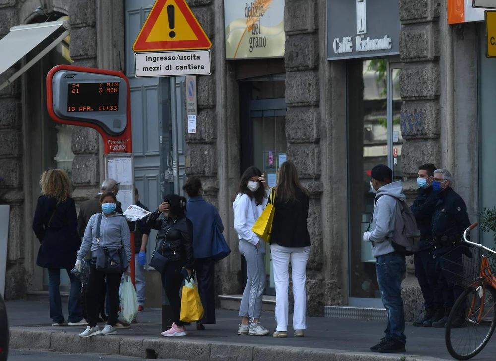 Người dân đợi xe buýt tại bến xe ở Milan, Italy ngày 18/4/2020 trong bối cảnh dịch COVID-19 đang hoành hành. Ảnh: THX/TTXVN