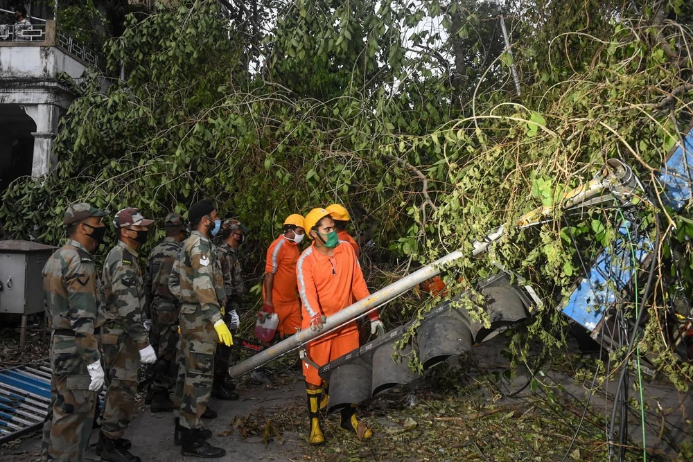 Quân đội Ấn Độ cùng với lực lượng ứng phó thảm họa quốc gia dọn dẹp cây đổ sau bão Amphan tại Kolkata, thủ phủ bang Tây Bengal ngày 23/5. (Ảnh: AFP/TTXVN)