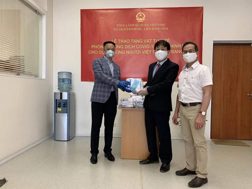 Tổng Lãnh sự Việt Nam tại thành phố Ekaterinburg Ngô Phương Nghị (giữa) trao tặng khẩu trang cho Hội người Việt Nam tỉnh Sverdlovsk. (Ảnh: TTXVN phát)