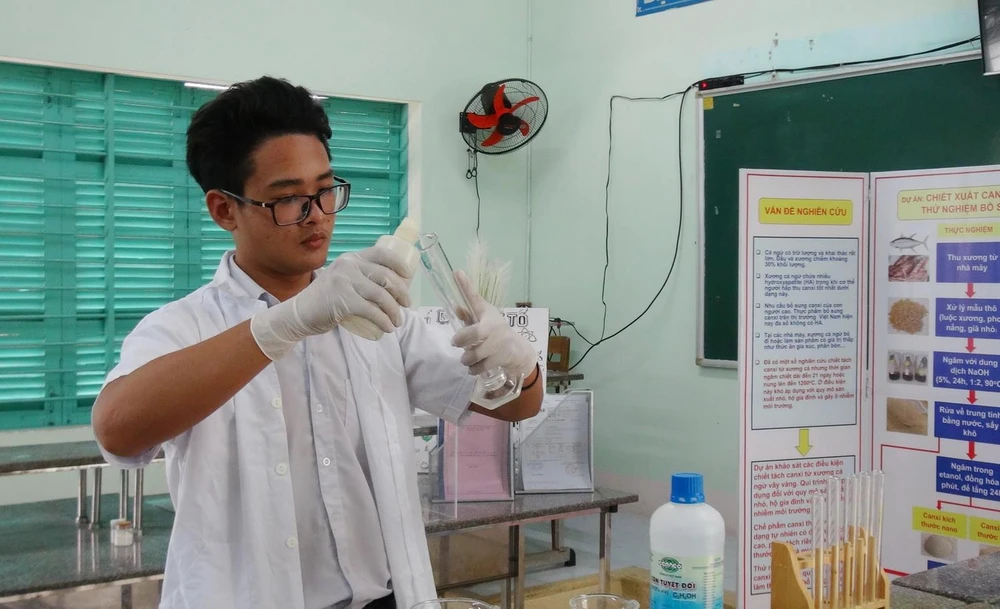 Em Trịnh Hoàng Long pha chế ngâm hóa chất với xương cá ngừ đã qua xử lý thô trong phòng thí nghiệm của trường THPT Nguyễn Văn Trỗi. (Ảnh: Phan Sáu/TTXVN)