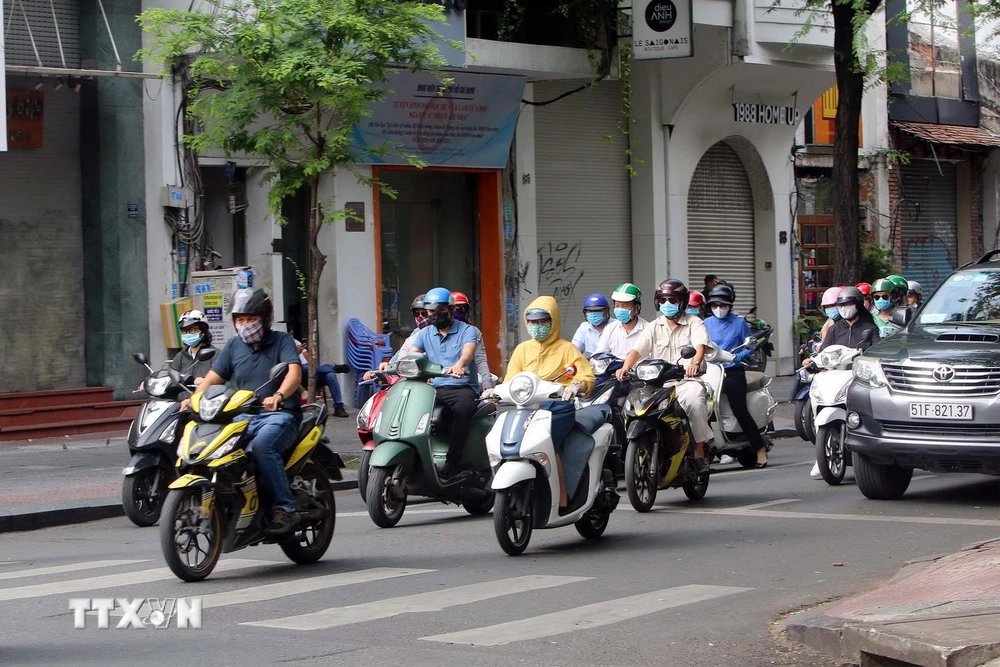 Người dân TP Hồ Chí Minh thực hiện đeo khẩu trang phòng chống dịch COVID-19 khi tham gia giao thông. (Ảnh: Thanh Vũ/TTXVN)