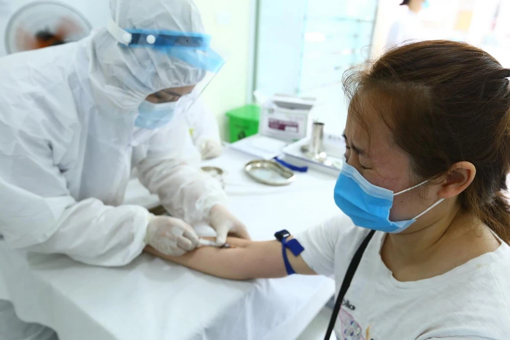 Nhân viên y tế lấy mẫu xét nghiệm nhanh cho người về từ Đà Nẵng, tại phường Bách Khoa và phường Cầu Dền, quận Hai Bà Trưng sáng 01/8. (Ảnh: Minh Quyết/TTXVN)
