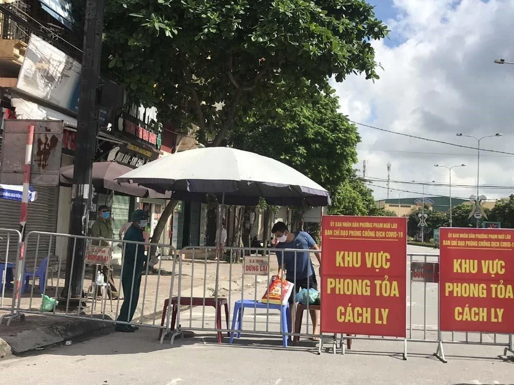 Người dân trong khu vực phong tỏa trên phố Ngô Quyền (Hải Dương) nhận thực phẩm tiếp tế tại hàng rào cách ly ngày 16/8. (Ảnh: Mạnh Minh/TTXVN)