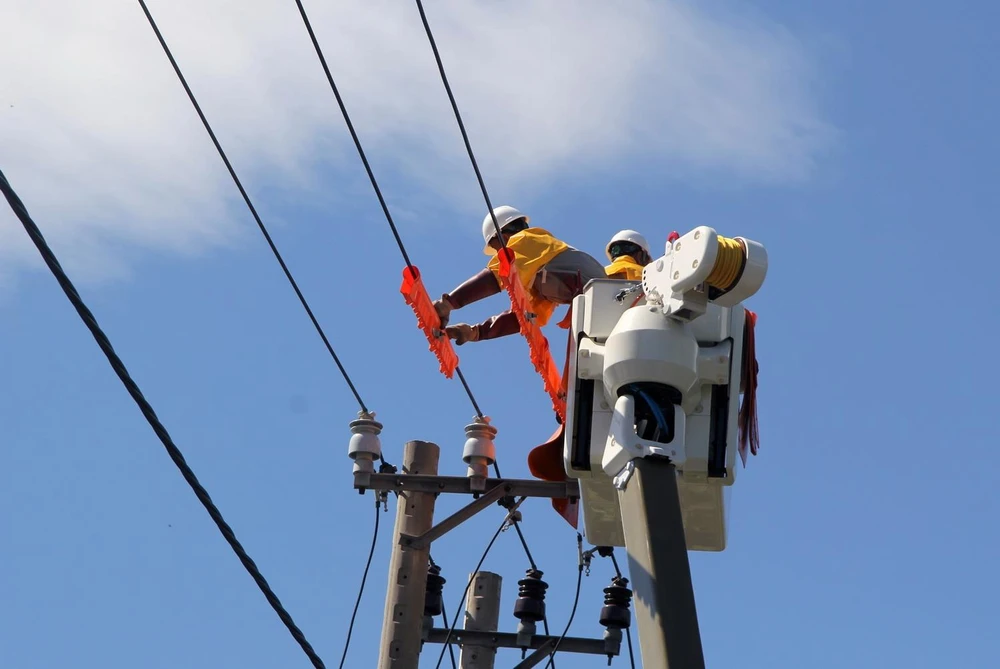 Công nhân kỹ thuật sửa chữa đường dây trung áp khi đang có điện. (Ảnh: Xuân Triệu/TTXVN)