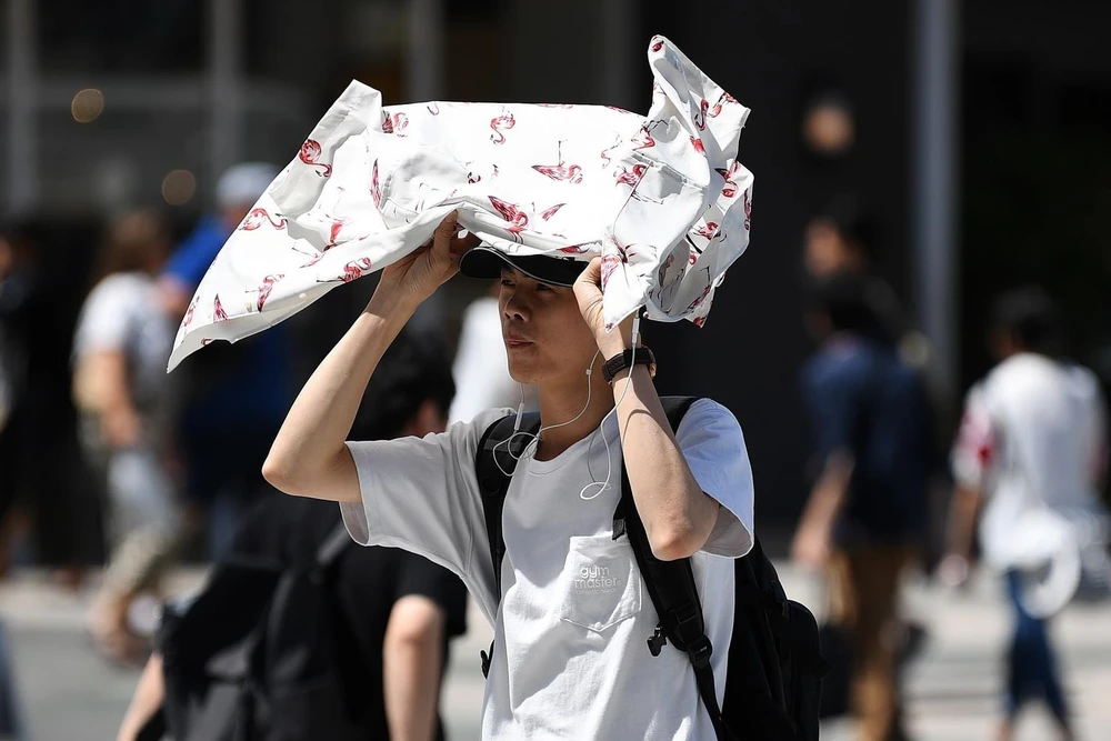 Người dân di chuyển trên đường phố dưới trời nắng nóng tại Tokyo, Nhật Bản. (Ảnh: AFP/ TTXVN)
