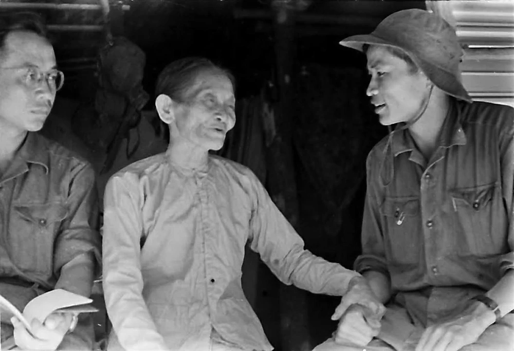 Phóng viên Thanh Phong của TTXGP tại Quảng Trị (bên phải) nói chuyện với một gia đình nuôi cán bộ cách mạng tại thị xã Quảng Trị năm 1968. (Ảnh: TTXVN) 