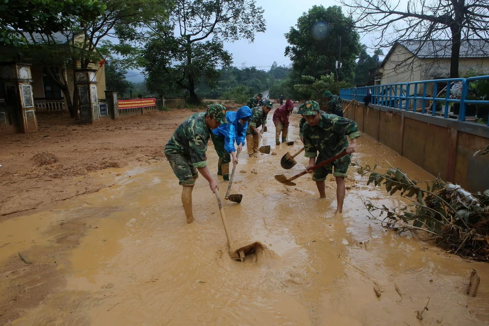 Bộ đội giúp địa phương xã Hướng Việt thu dọn bùn đất trên các tuyến giao thông. (Ảnh: Hồ Cầu/TTXVN)