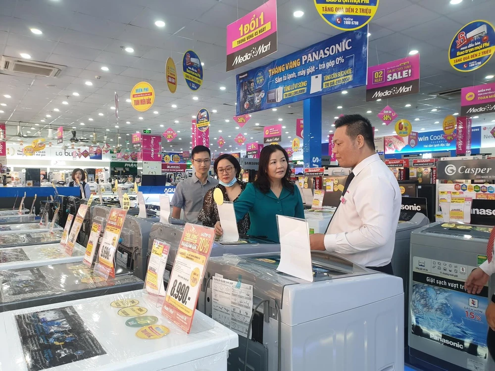 Bà Trần Thị Phương Lan, Phó Giám đốc phụ trách Sở Công Thương Hà Nội (áo xanh) đi kiểm tra tại siêu thị điện máy MediaMart Phạm Văn Đồng. (Ảnh: Phương Anh/TTXVN)