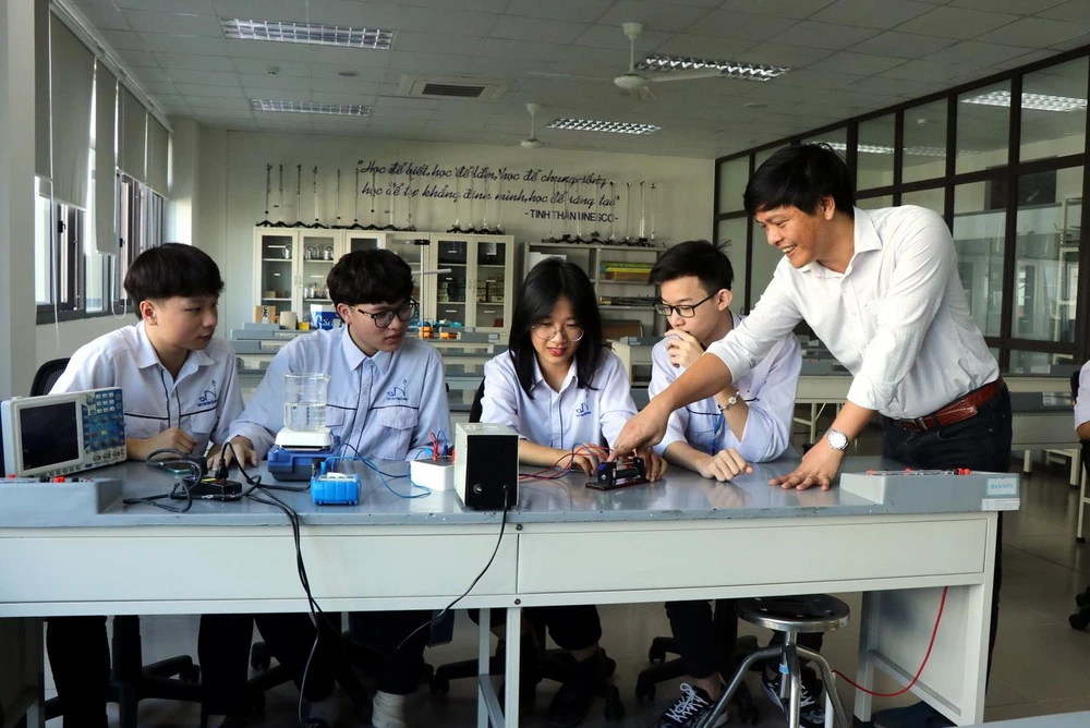 Thầy giáo trường THPT chuyên Bắc Ninh hướng dẫn những học sinh vừa đạt giải cuộc thi Olympic trẻ thế giới làm thí nghiệm Vật lý. (Ảnh: Đinh Văn Nhiều/TTXVN)