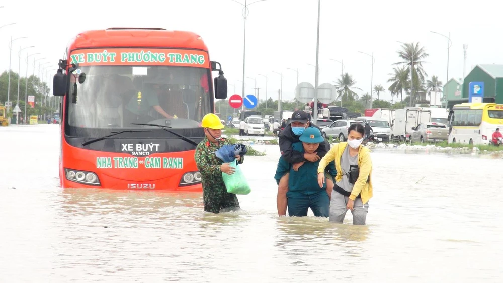 Lực lượng quân đội hỗ trợ cứu nạn người dân bị mắc kẹt trong xe buýt đến nơi an toàn. (Ảnh: Phan Sáu/Vietnam+)