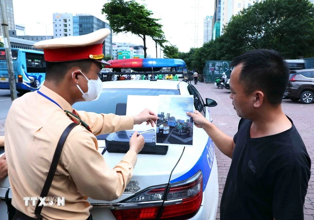 Lực lượng CSGT cho tài xế xe khách xem lại hình ảnh vi phạm để làm căn cứ xử phạt theo quy định pháp luật. (Ảnh: Phạm Kiên/TTXVN)