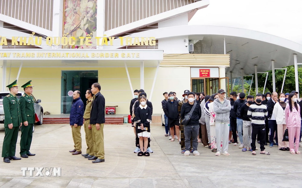 Lực lượng chức năng hai nước làm thủ tục trao trả 69 công dân tại Cửa khẩu Quốc tế Tây Trang. (Ảnh: TTXVN phát)