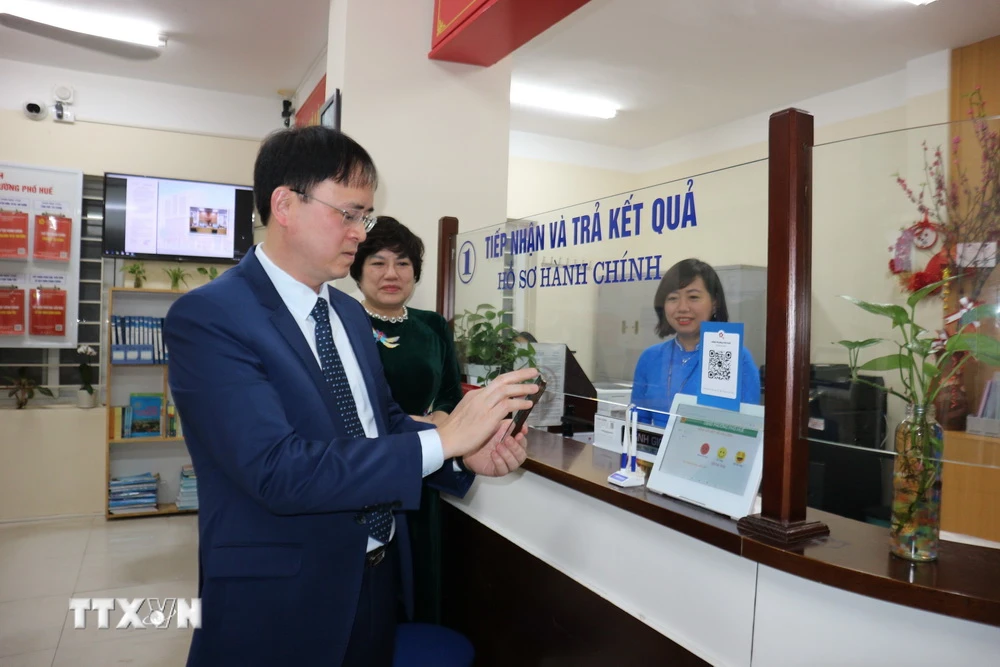 Ông Nguyễn Quang Trung, Chủ tịch UBND quận Hai Bà Trưng kiểm tra việc giải quyết thủ tục hành chính qua môi trường điện tử cho người dân tại phường Phố Huế. (Ảnh: Mạnh Khánh/TTXVN)
