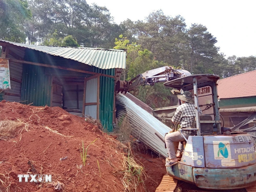 Lực lượng chức năng cưỡng chế, tháo dỡ các trường hợp xây dựng nhà, lều tạm trên đất rừng ven đường Hồ Chí Minh, đoạn qua xã Nâm N’jang, huyện Đắk Song, tỉnh Đắk Nông. (Ảnh: TTXVN phát)