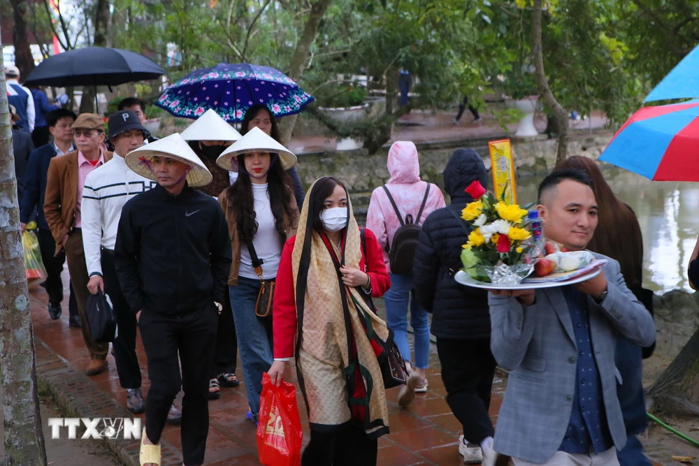 Mặc dù trời mưa nhẹ nhưng chiều tối ngày 14 tháng Giêng đông đảo du khách đến đền Trần để tham quan, vãn cảnh. (Ảnh: Công Luật/TTXVN)