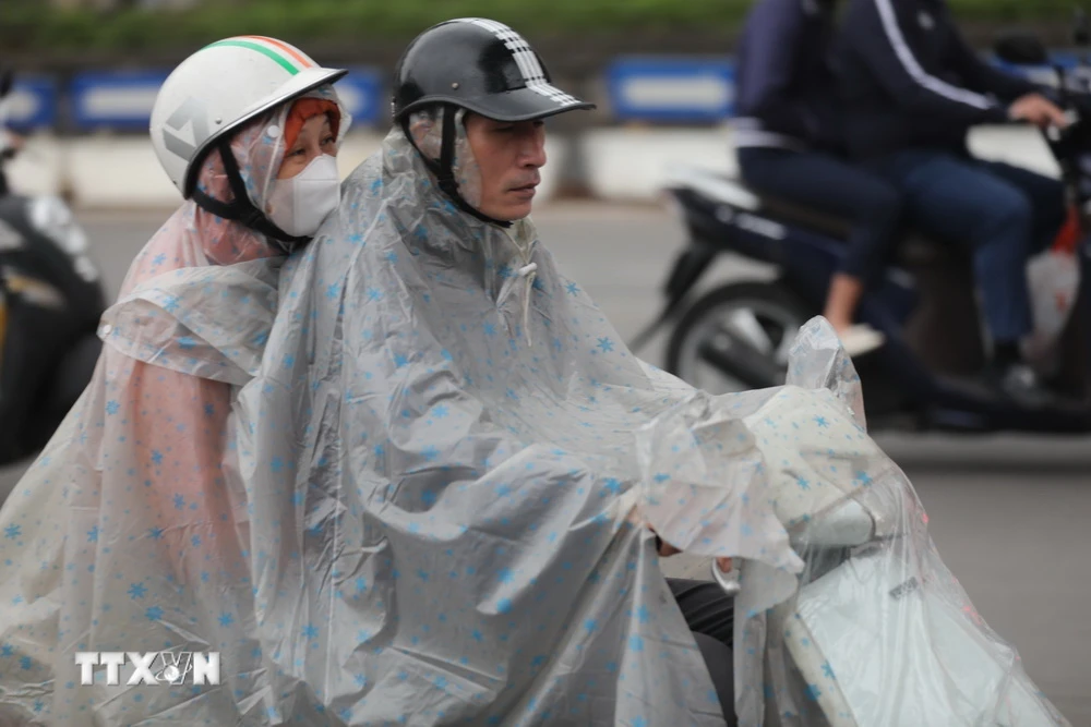 Do thời tiết có gió lạnh kèm mưa nên nhiều người mặc áo mưa khi tham gia giao thông. (Ảnh: Thanh Tùng/TTXVN)