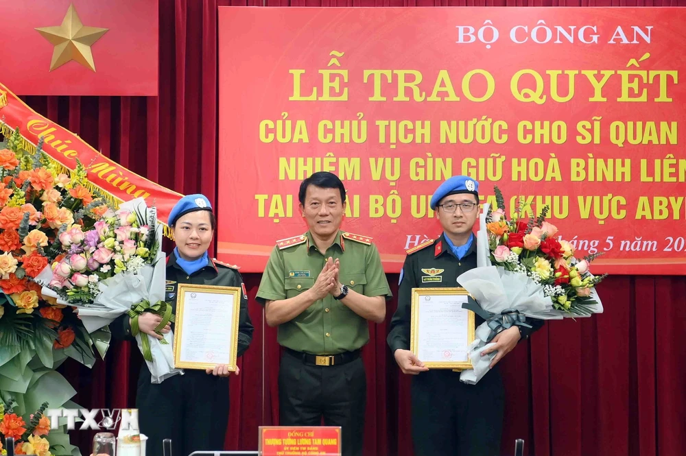 Thượng tướng Lương Tam Quang, Thứ trưởng Bộ Công an trao Quyết định của Chủ tịch nước cho 2 sỹ quan Công an Nhân dân đi thực hiện nhiệm vụ gìn giữ hòa bình Liên hợp quốc. (Ảnh: TTXVN phát)
