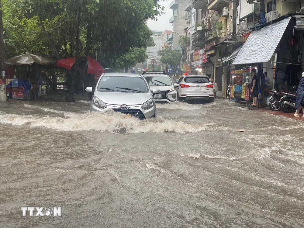 Khu vực Vĩnh Hưng, quận Hoàng Mai, các phương tiện tham gia giao thông gặp khó khăn khi mưa lớn và sấm sét liên tục. (Ảnh: Phạm Tuấn Anh/TTXVN)