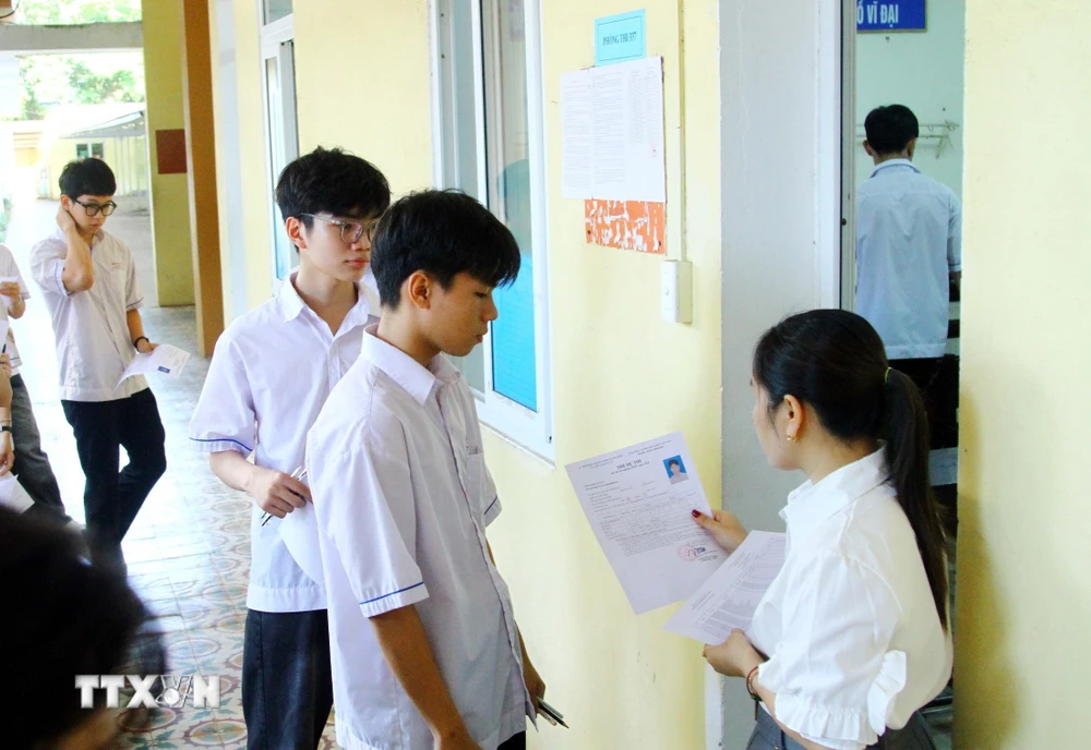 Giám thị kiểm tra thẻ dự thi của các thí sinh trước khi vào phòng thi tại điểm thi Trường THPT Đào Duy Từ, thành phố Đồng Hới, tỉnh Quảng Bình. (Ảnh: Tá Chuyên/TTXVN)
