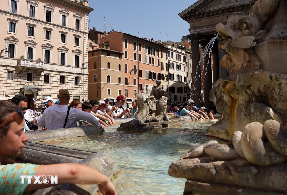 Khách du lịch tránh nóng bên đài phun nước tại Rome, Italy. (Ảnh: THX/TTXVN)