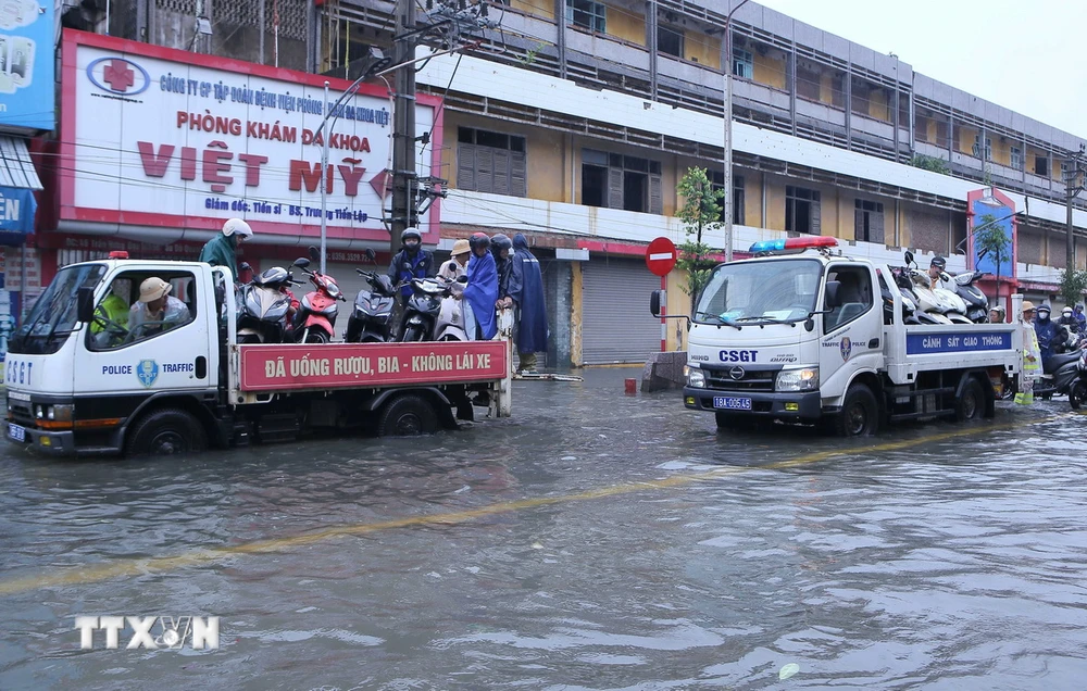 Lực lượng Cảnh sát Giao thông thành phố Nam Định dùng xe chuyên dụng đưa người dân và phương tiện qua điểm ngập lụt tại khu vực chân cầu Đò Quan. (Ảnh: Công Luật/TTXVN)