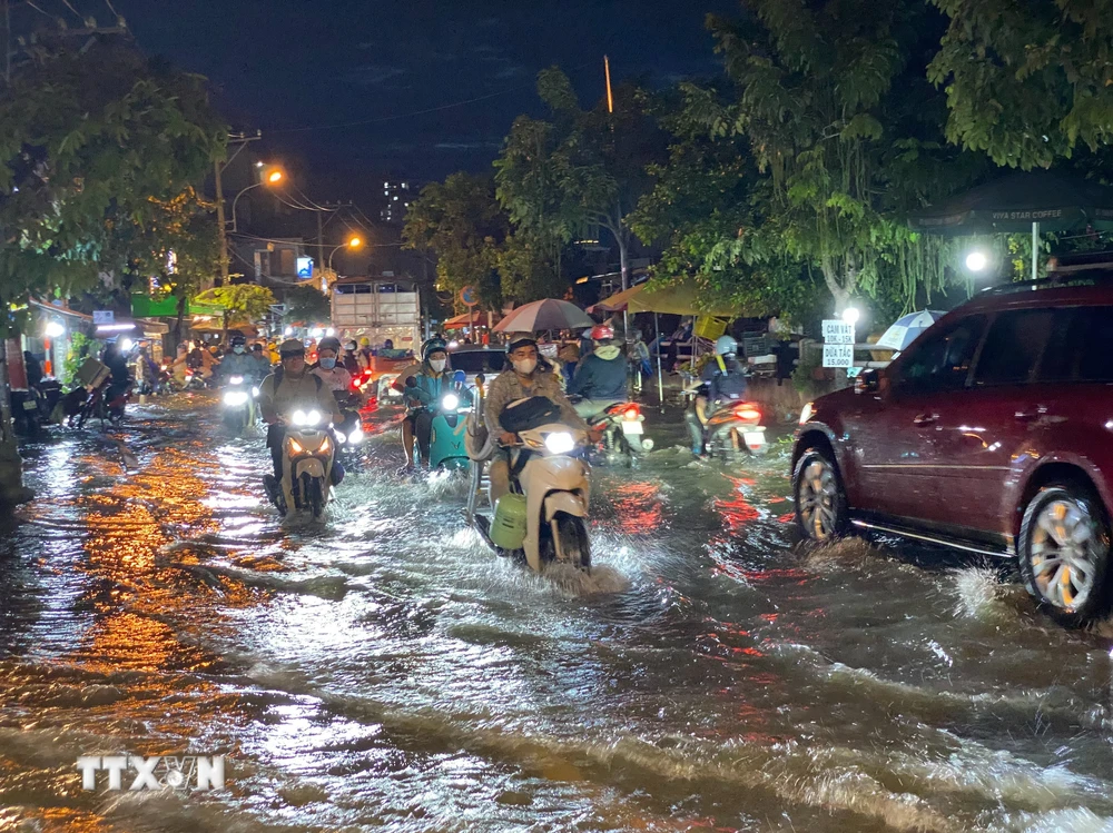 Các phương tiện di chuyển khó khăn khi triều cường gây ngập trên đường Trần Xuân Soạn, quận 7. (Ảnh: Hồng Giang/TTXVN)