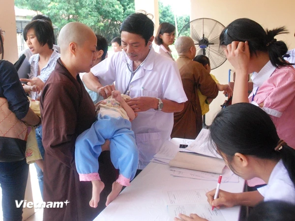 Nhân viên trung tâm bảo trợ xã hội chăm sóc trẻ em tại trung tâm. (Ảnh: PV/Vietnam+)