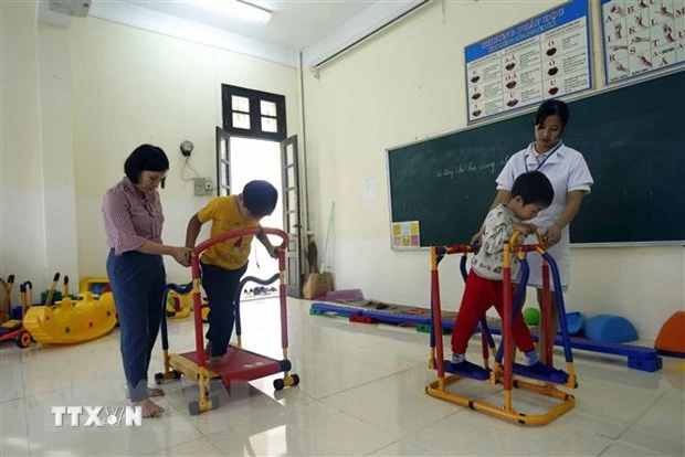 Nhân viên công tác xã hội tập phục hồi chức năng cho các học sinh khuyết tật. (Ảnh: Phạm Kiên/TTXVN)