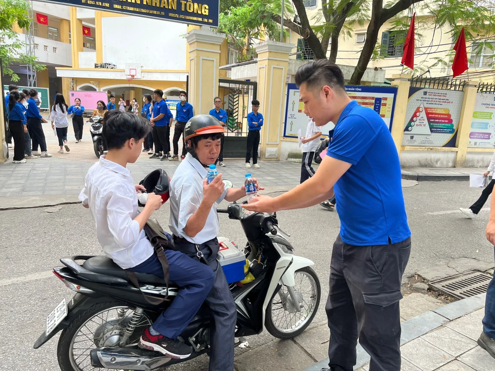 Tình nguyện viên hỗ trợ nước uống cho sỹ tử, phụ huynh tại điểm thi trường Trung học phổ thông Trần Nhân Tông. (Ảnh: PV/Vietnam+)