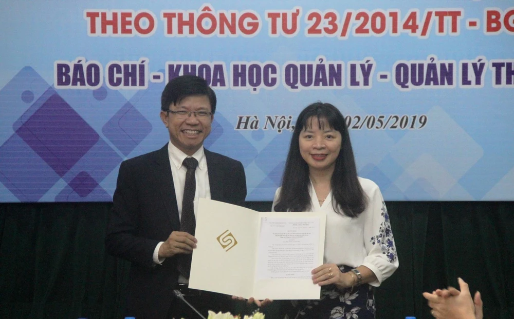 Phó hiệu trưởng Hoàng Anh Tuấn trao quyết định mở chương trình đào tạo chất lượng cao xã hội hóa ngành Báo chí cho Viện trưởng Viện Báo chí và Truyền thông Đặng Thị Thu Hương. (Ảnh: PV/Vietnam+)