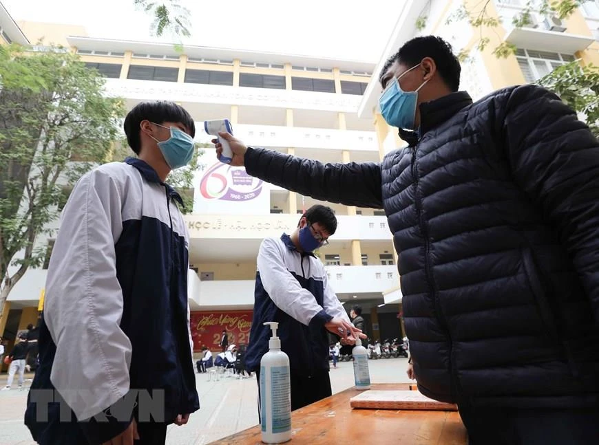 Học sinh Hà Nội được đo thân nhiệt, sát khuẩn trước khi vào trường. (Ảnh: Thành Đạt/TTXVN)