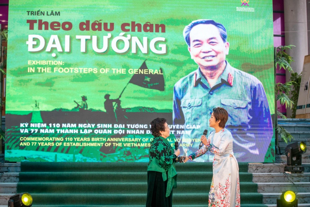 Nhà thơ Nguyễn Thị Mỹ Dung (trái) và ca sỹ Mỹ Linh ngẫu hứng trong lễ khai mạc triển lãm. (Ảnh: Minh Sơn/Vietnam+)