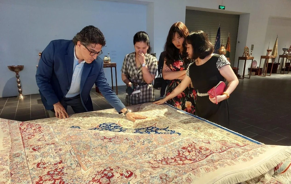 Khách tham quan chiêm ngưỡng những tấm thảm Iran nổi danh thế giới về độ tinh xảo. (Ảnh: Minh Thu/Vietnam+)