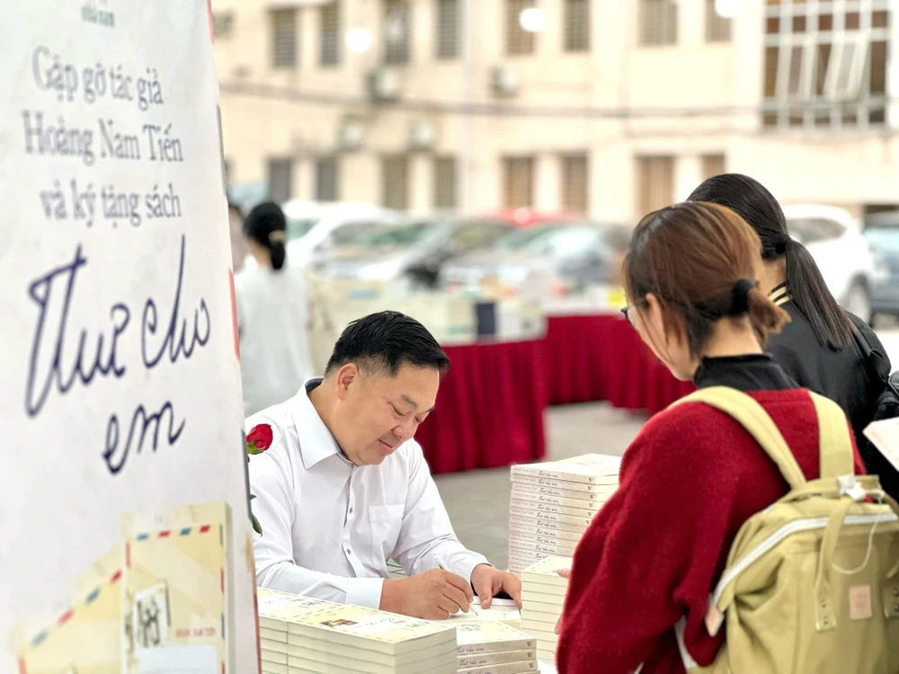 Tác giả Hoàng Nam Tiến ký tặng sách cho độc giả tại Hội sách Nhã Nam (Hà Nội) ngày 9/4. (Ảnh: PV/Vietnam+)