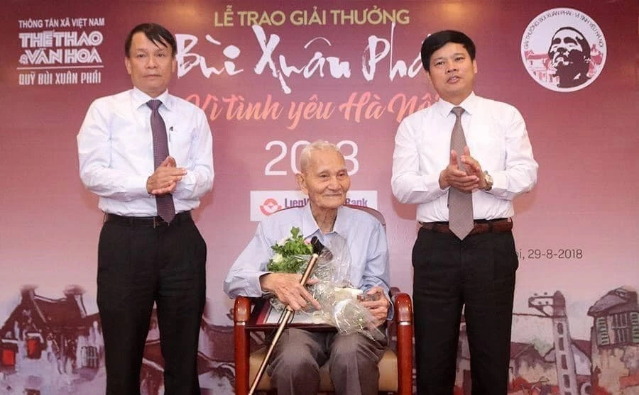 Ông Nguyễn Bá Đạm (giữa) nhận Giải thưởng Lớn-Vì tình yêu Hà Nội trong hệ thống Giải thưởng Bùi Xuân Phái-Vì tình yêu Hà Nội năm 2018. (Ảnh: TTXVN)